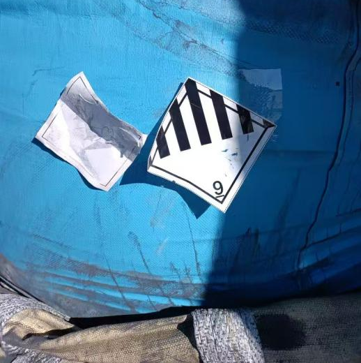 Hazard label peeling off from polyethylene bag - insecure attachment