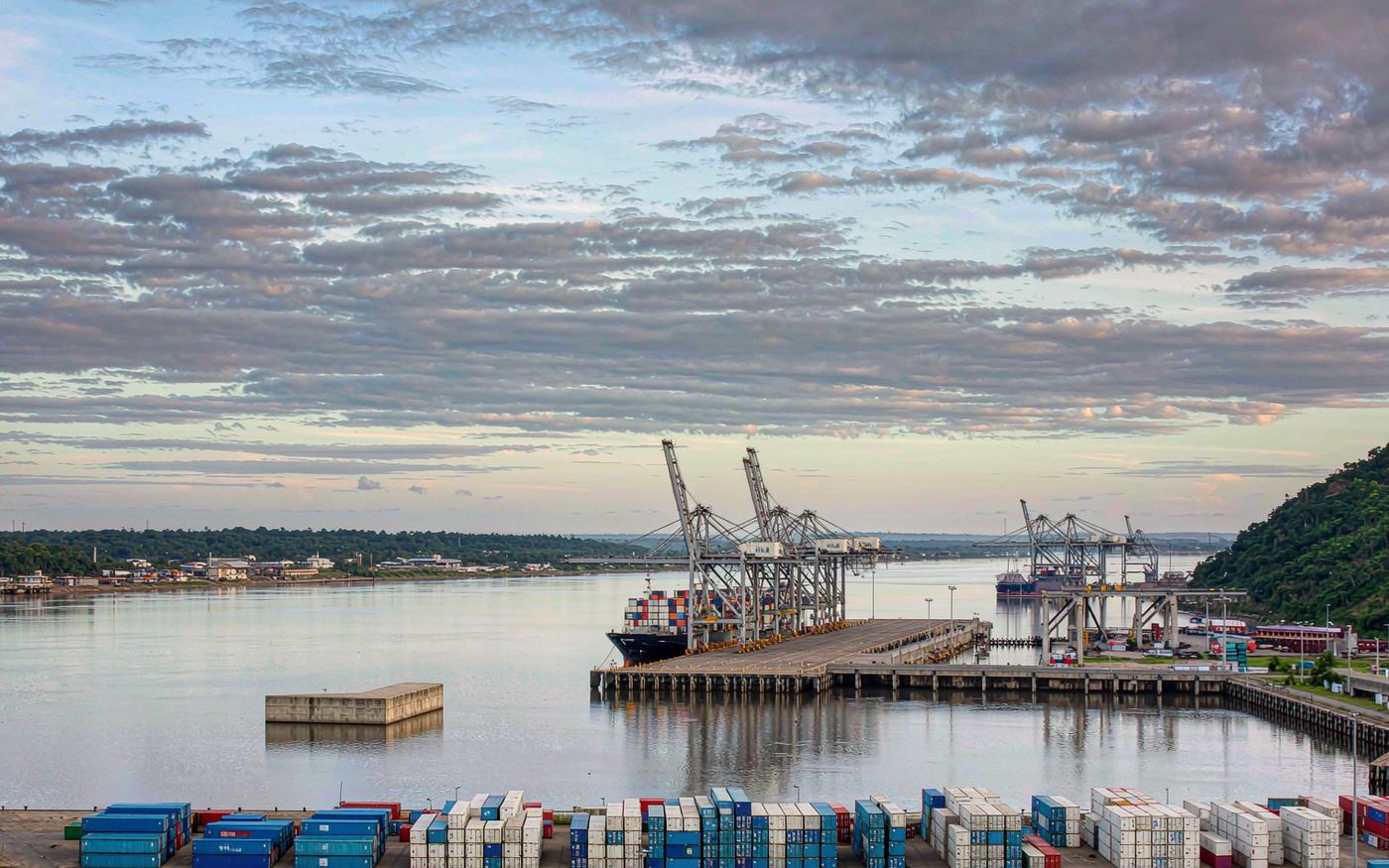 Container port at Douala in Cameroon with gantry cranes over a container vessel and stacked shipping containers