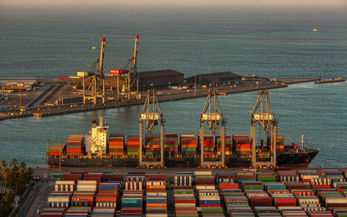 Container port at Pointe-Noire in the Republic of the Congo with gantry cranes over a container vessel and stacked shipping containers