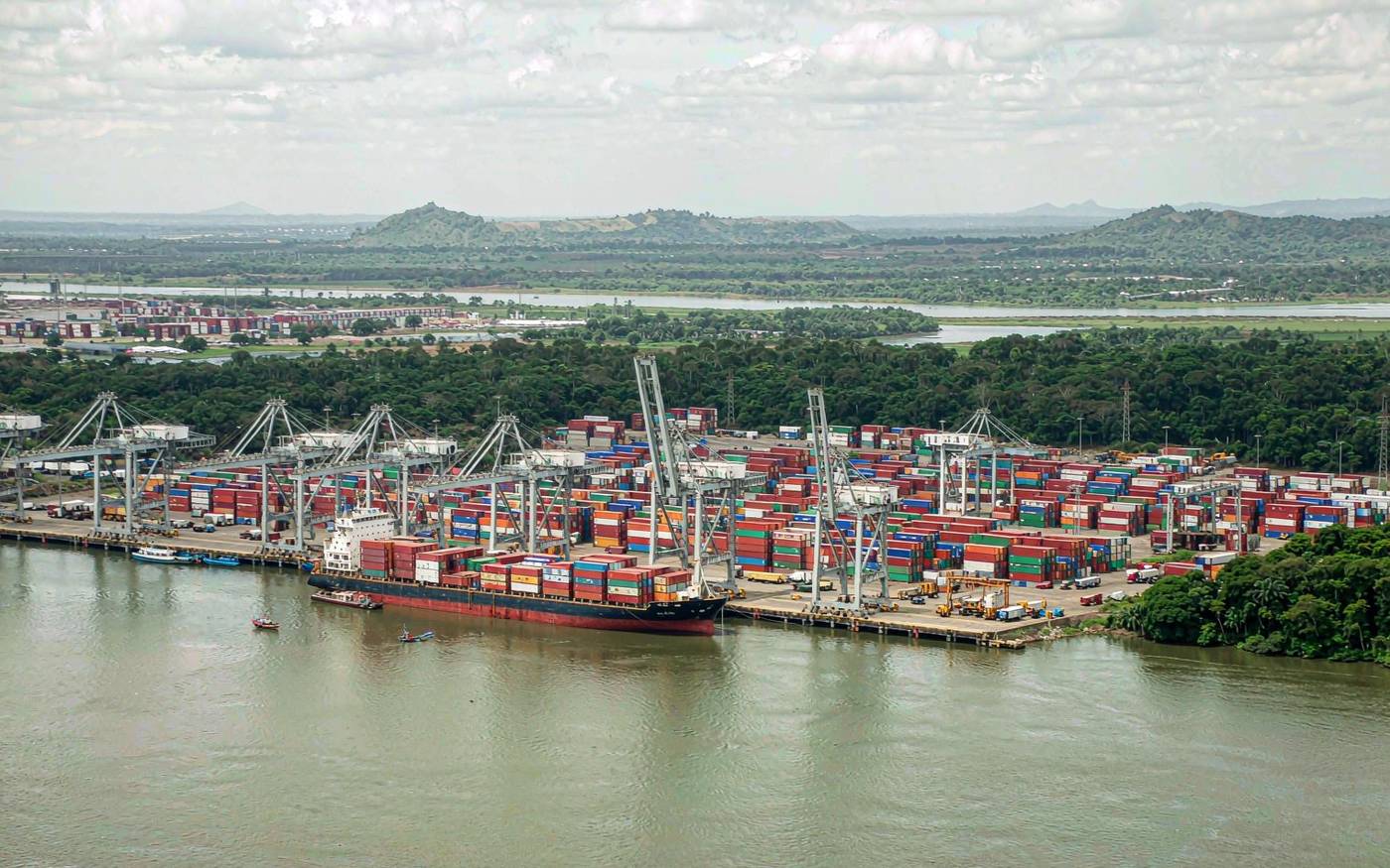 Container terminal at the port of Matadi in the DR Congo with gantry cranes and a container vessel on the Congo River