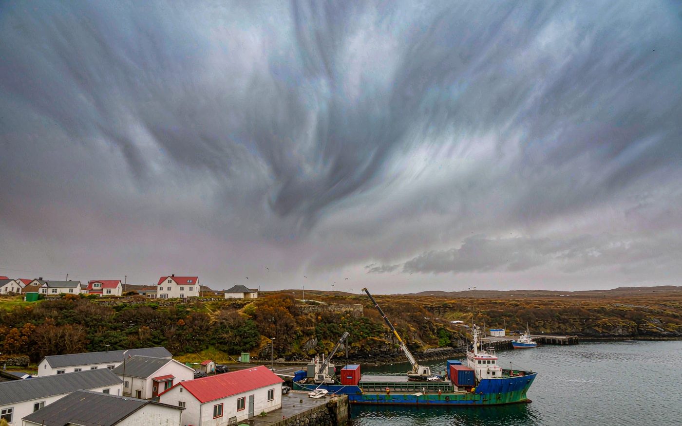 A cargo ship working containers on the quay of a small sub-polar harbour in the Falkland Islands