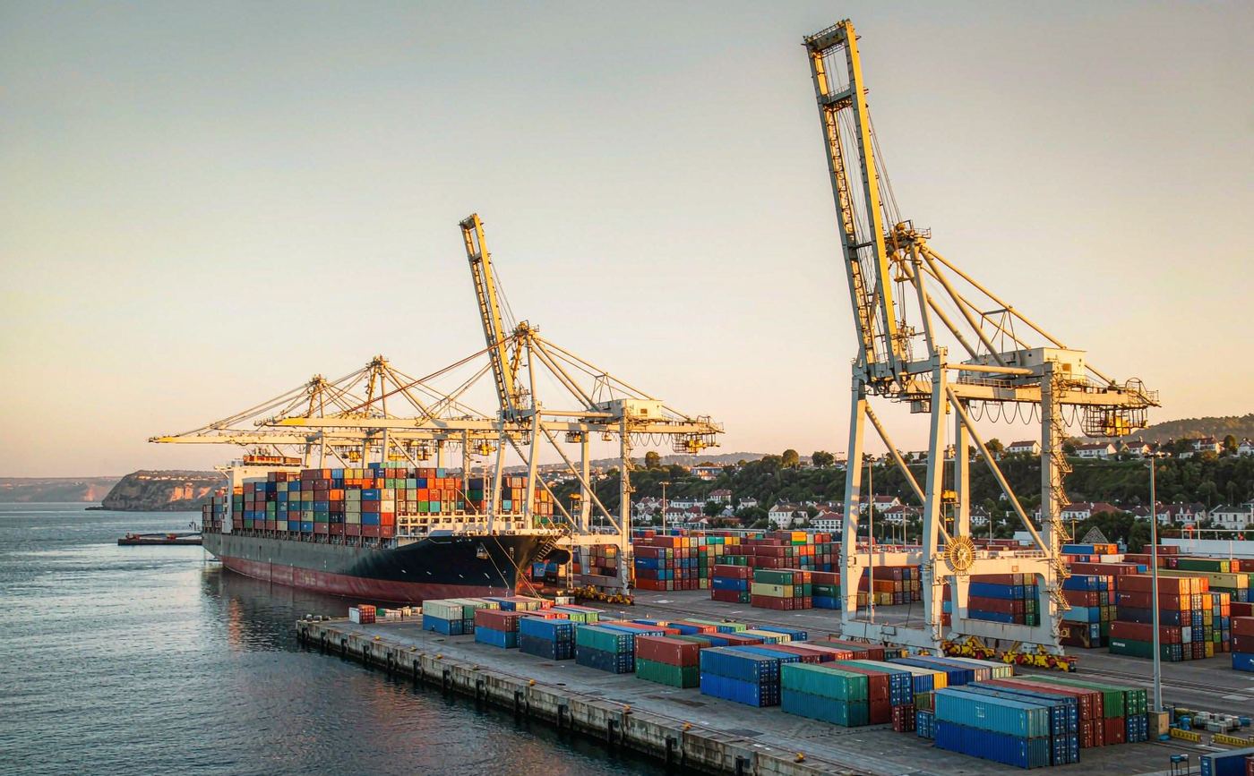 French container port with ship-to-shore gantry cranes, stacked containers and a vessel berthed alongside