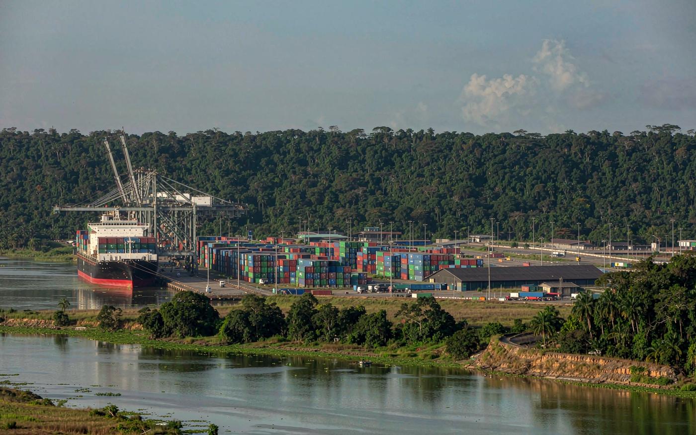 Container port at Owendo near Libreville in Gabon with a container ship, gantry cranes and rainforest hills behind
