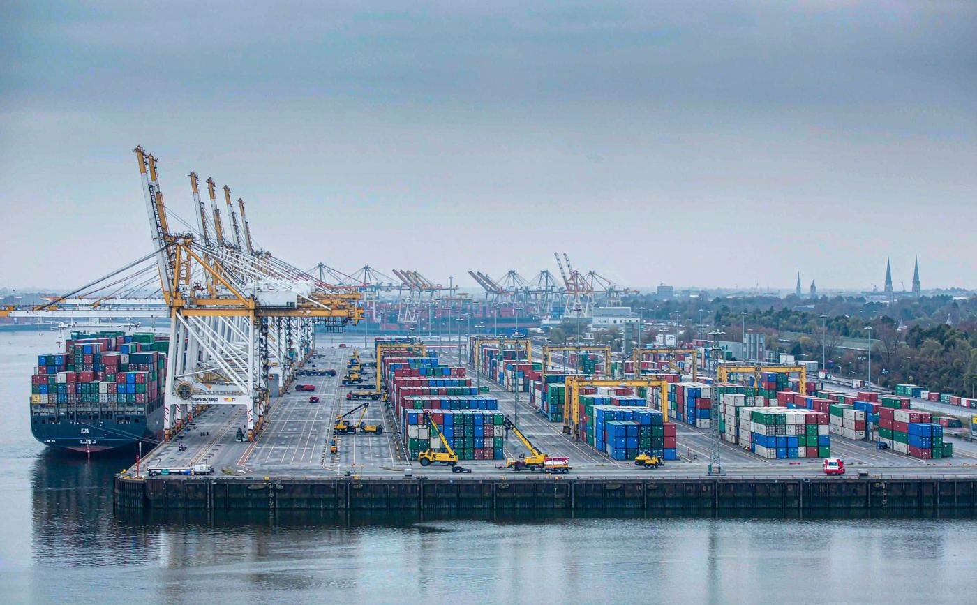Container terminal at the Port of Hamburg with ship-to-shore gantry cranes, stacked containers and a vessel berthed alongside