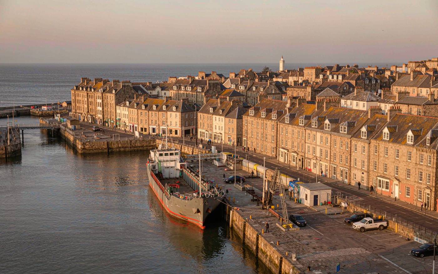 The harbour at St Peter Port, Guernsey, with a small cargo vessel at the quay and the town rising behind it