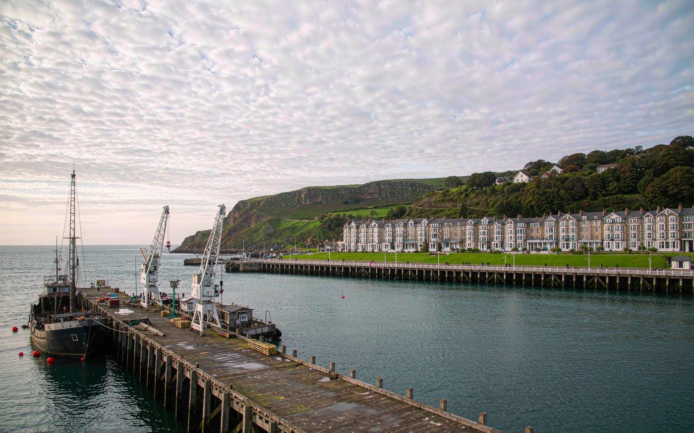 Douglas harbour on the Isle of Man with a cargo vessel at the quay and the town and green hills behind
