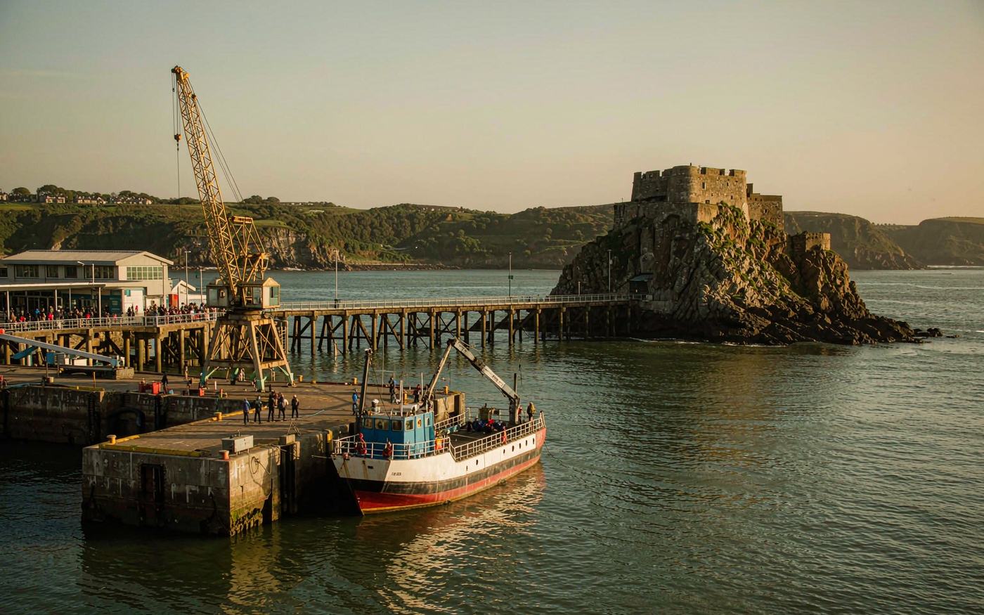The working harbour at St Helier, Jersey, with cargo quays, a harbour crane and the tidal island fort beyond