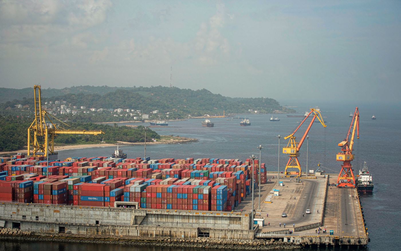 Freeport of Monrovia in Liberia with stacked containers, mobile harbour cranes and a container vessel