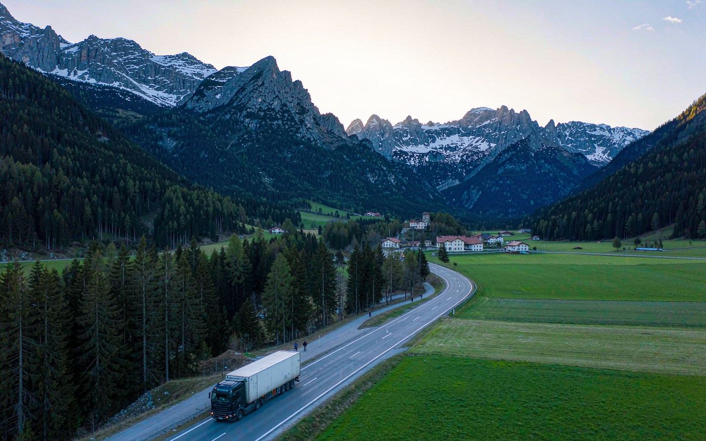 Cargo truck on an Alpine highway heading toward a small mountain town in Liechtenstein