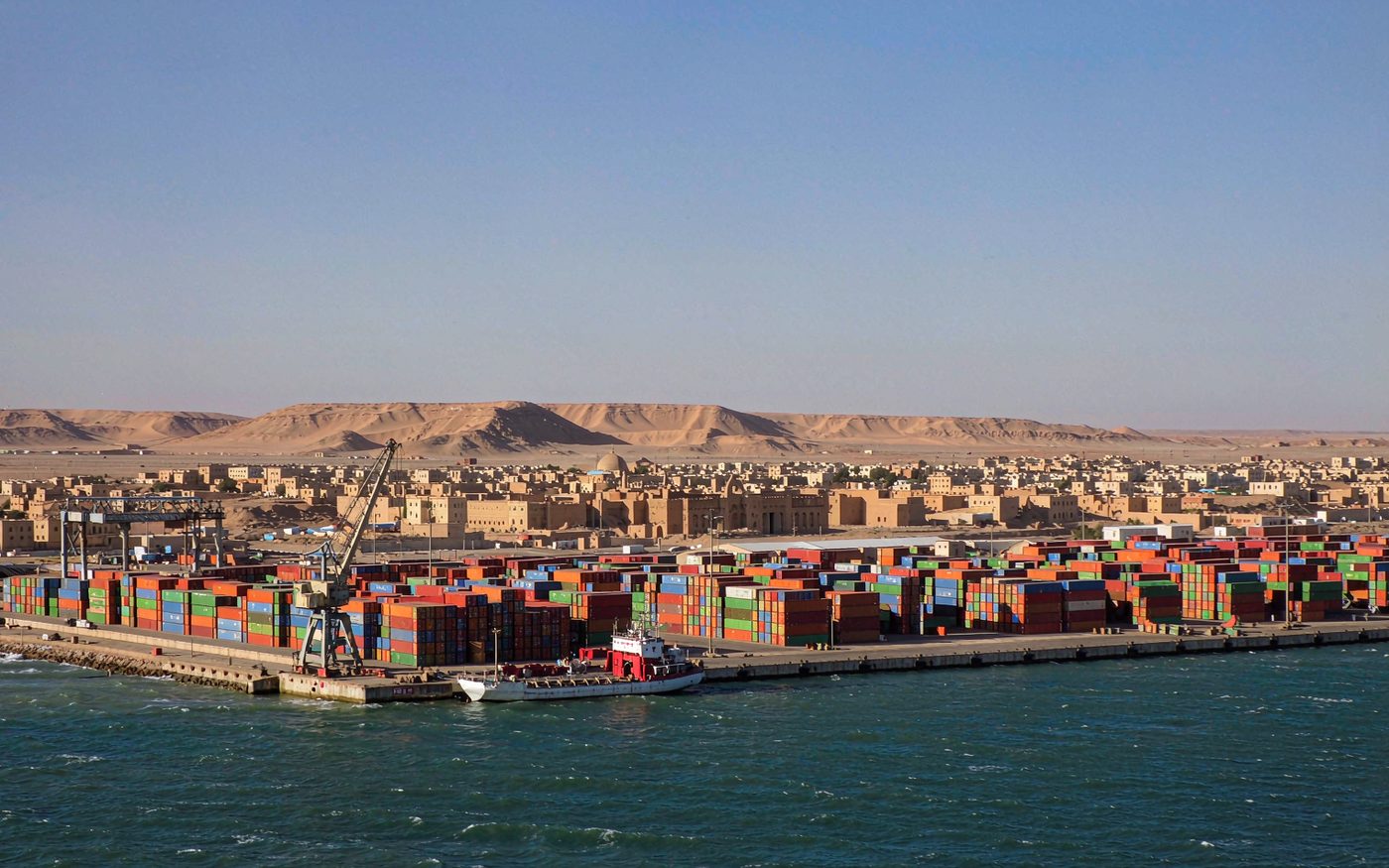 Port de l'Amitie at Nouakchott in Mauritania with stacked containers, mobile cranes and desert dunes behind