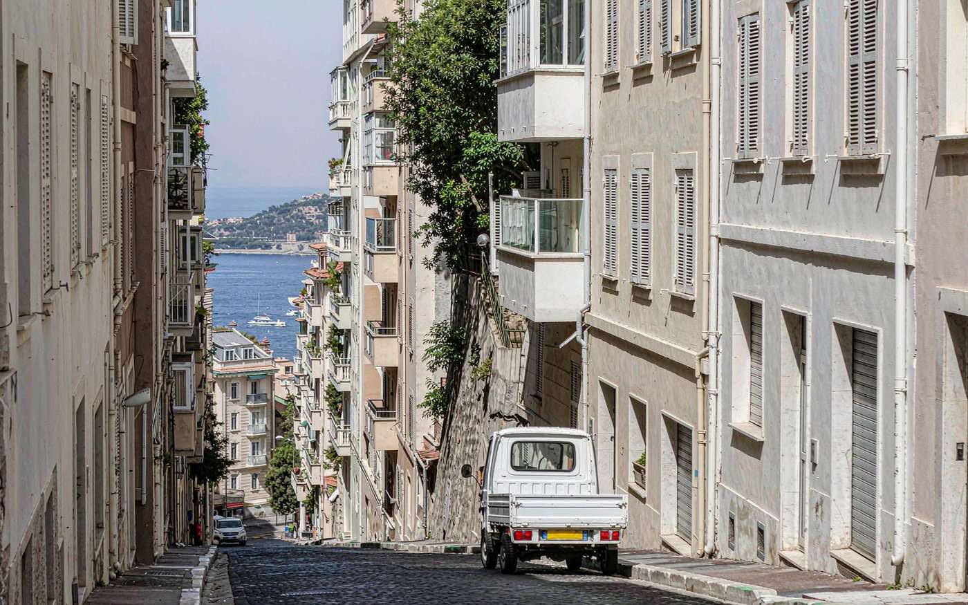 A small delivery van on a narrow street in the old town of Monaco above the Mediterranean