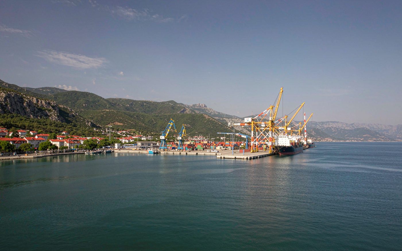 Container cranes and a cargo vessel at the port of Bar with mountains behind in Montenegro