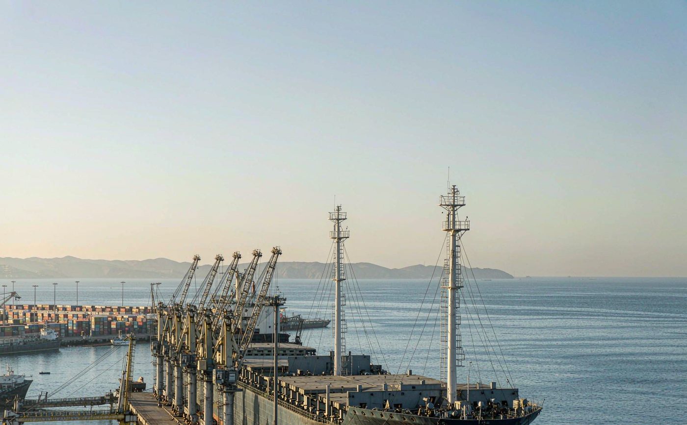 Atlantic container port with a row of gantry cranes, stacked containers in the yard and a vessel alongside the quay