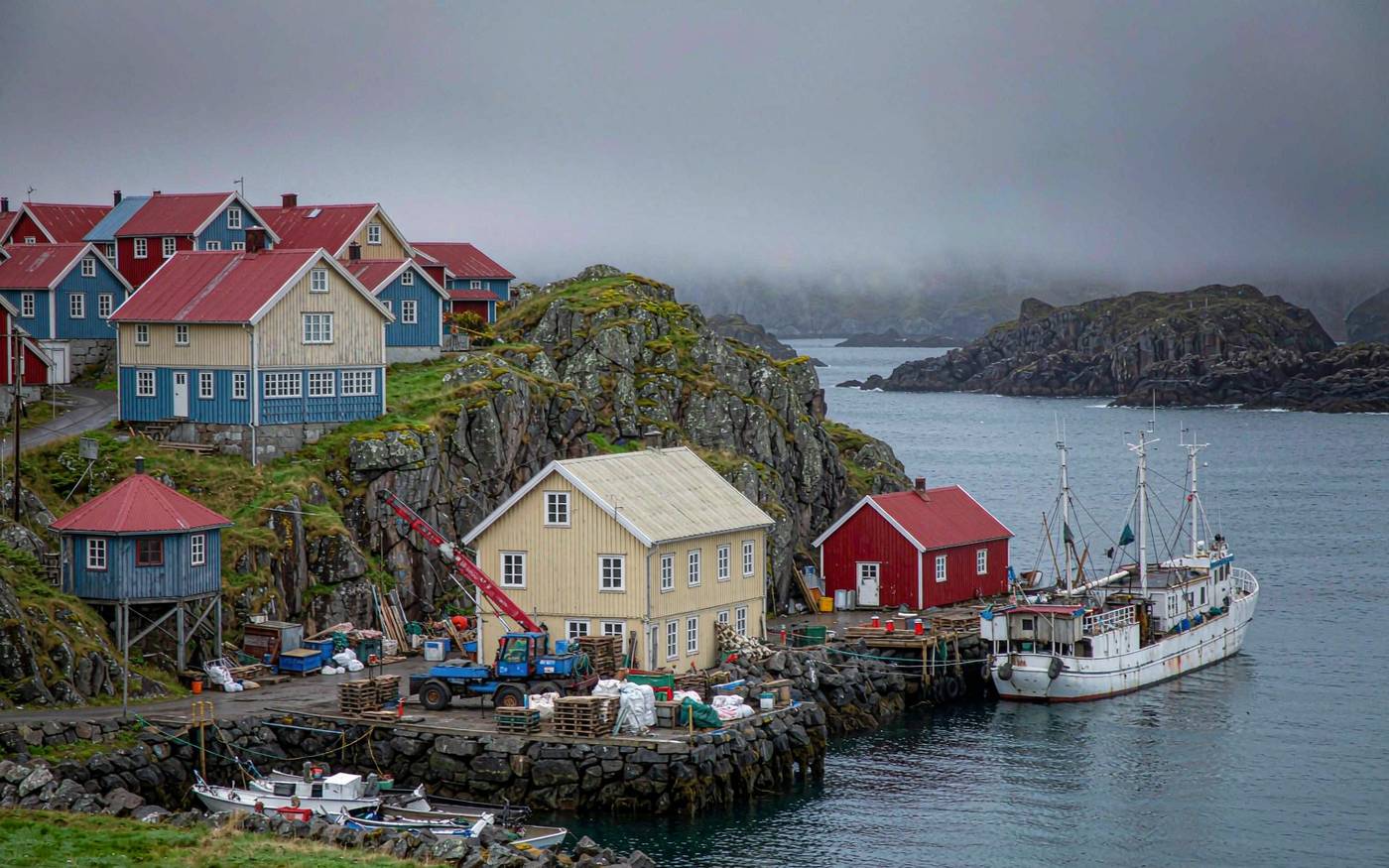 A small North Atlantic harbour with colourful wooden houses, a working quay and a supply vessel alongside