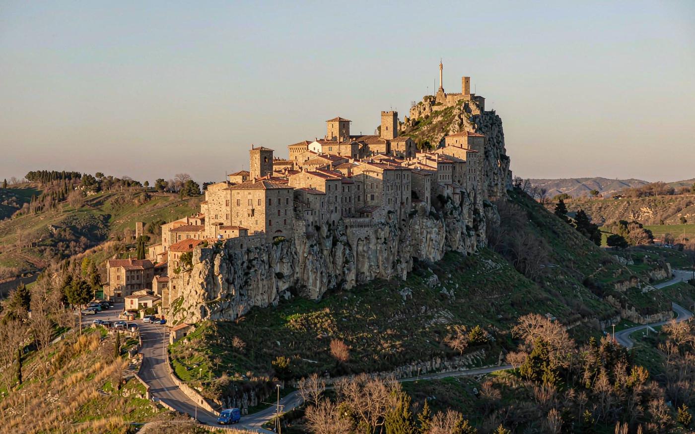 Walled hilltop town of San Marino on a rocky ridge with a winding road below