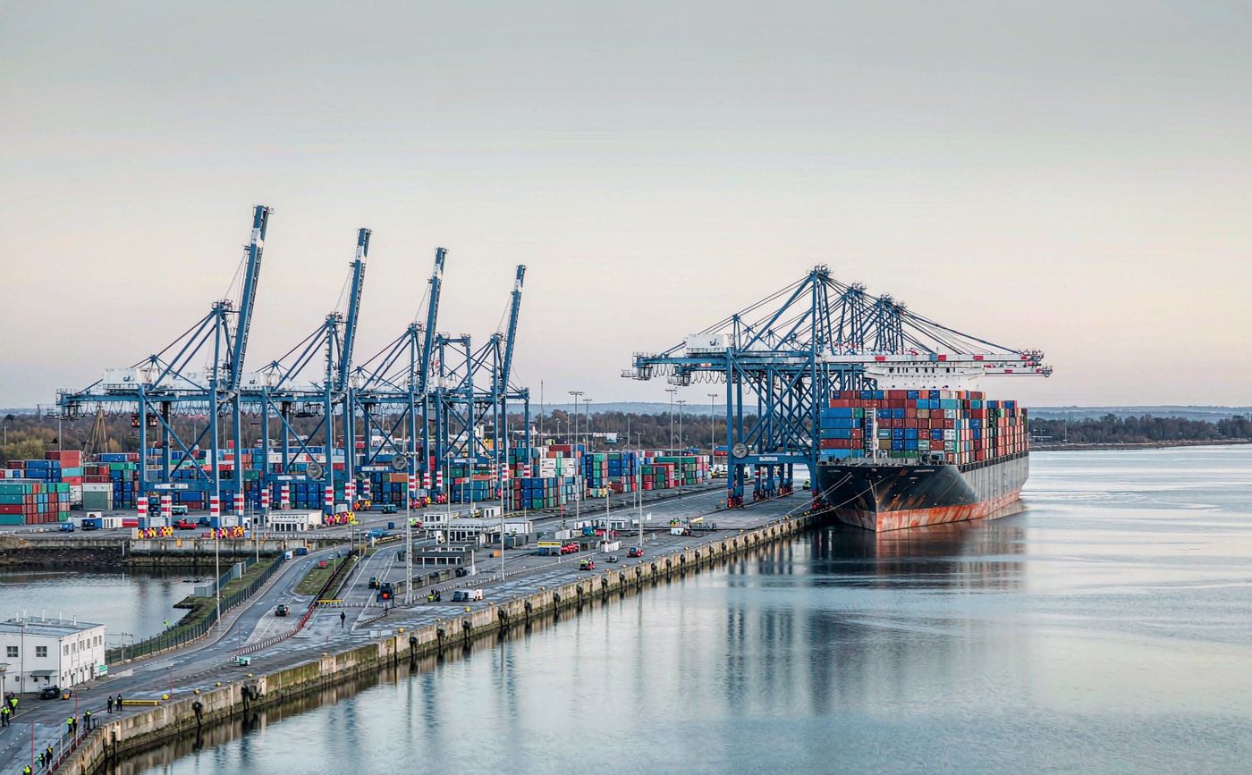 British deep-sea container port with ship-to-shore gantry cranes, stacked containers and a vessel berthed alongside