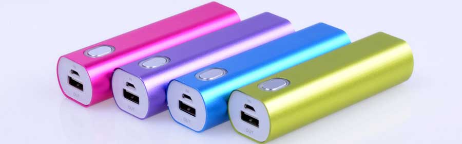Four colourful slim power banks in pink, purple, blue and lime green lying in a row on a white surface