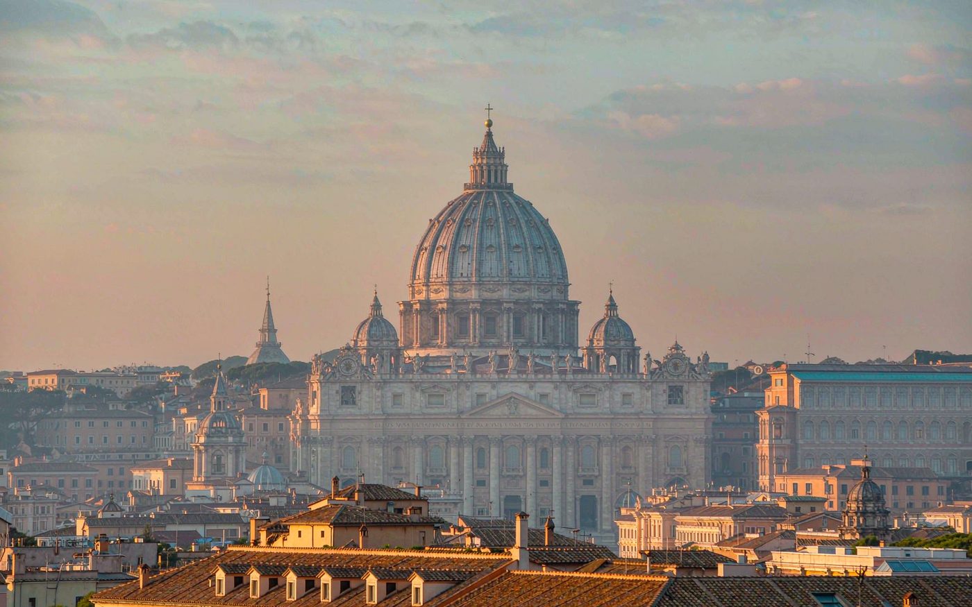The dome of Saint Peter's Basilica and the Vatican seen across the rooftops of Rome at dawn