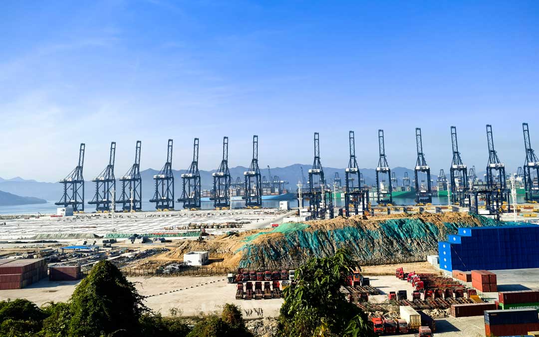 array of gantry cranes at a container terminal seen from a distance