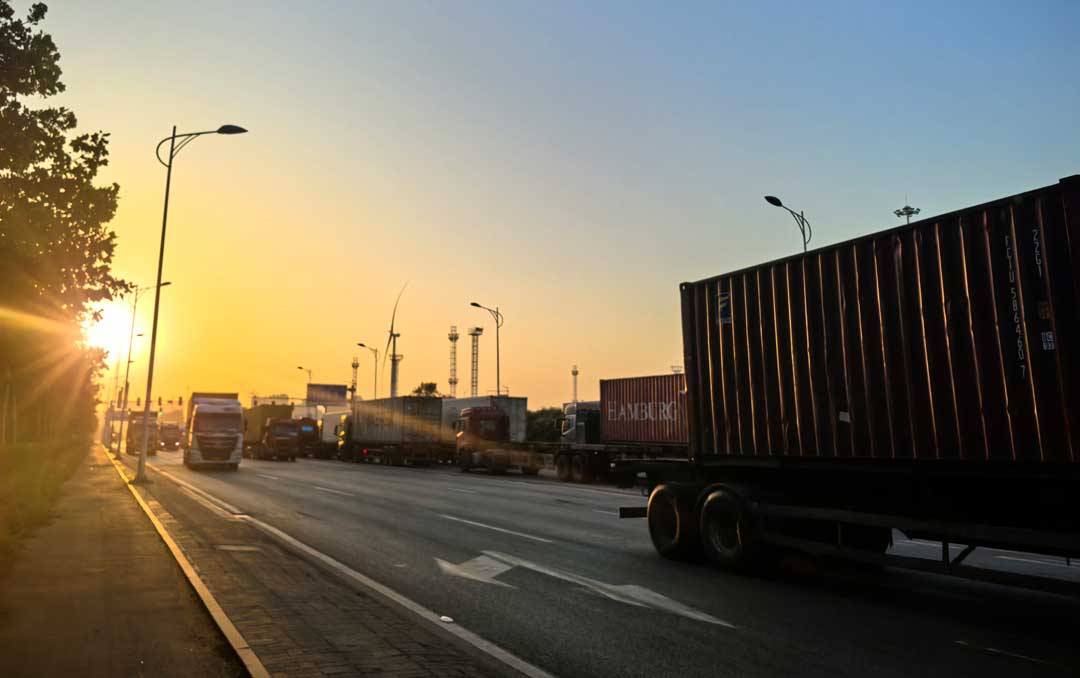 container truck fleet on a highway at sunset